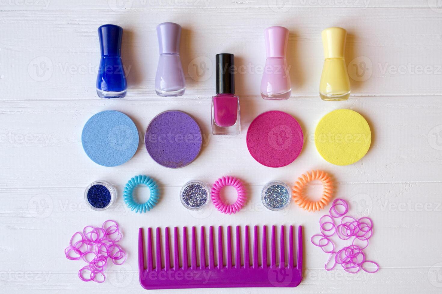 Colorful and bright cosmetics. Beauty care tools. Beauty salon. Girl's paradise. Nail polishes, sequins, pink hair bands and comb on the white wooden desk. Bright still life of beauty instruments. photo