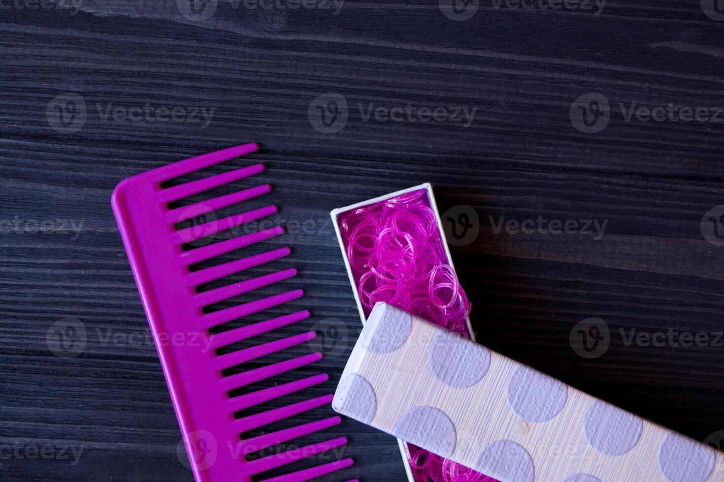 Beauty care tools. Beauty salon. Girl's paradise. Pink hair bands and comb on a dark blue wooden desk. Bright still life of beauty instruments. photo