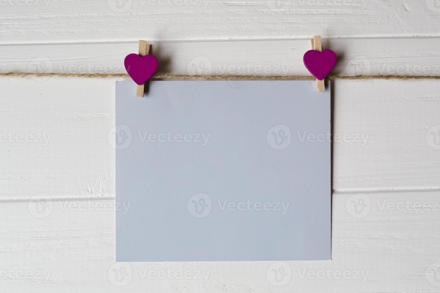 Blue memo sheet fastened with a decorative pin on a white wooden board. photo