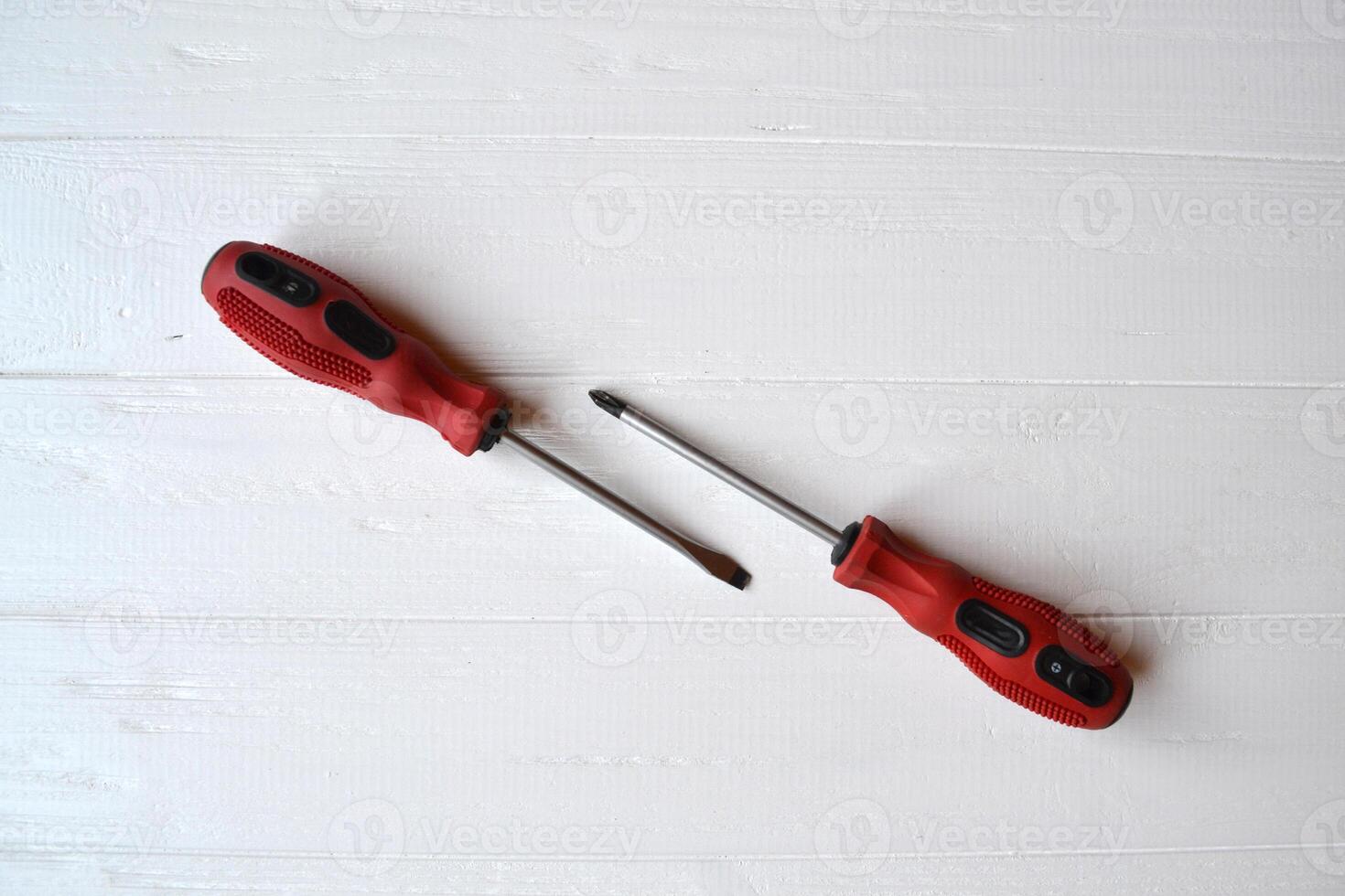 Red screwdrivers isolated on the white wooden background. photo