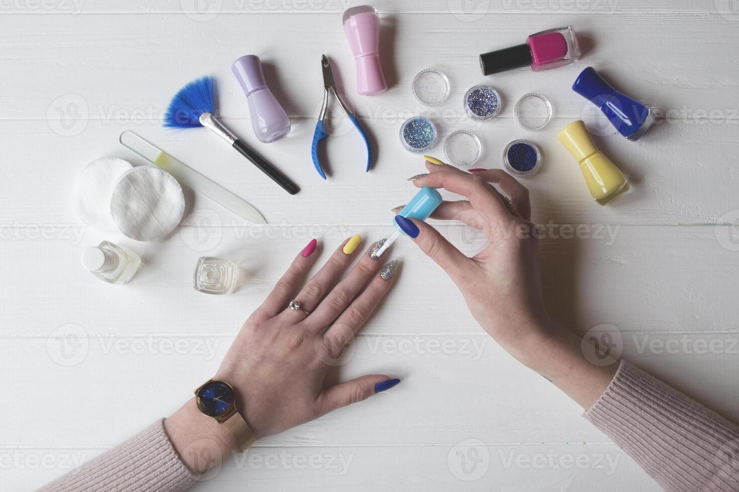 un mujer pintura su clavos. herramientas para manicura en un blanco de madera mesa. foto