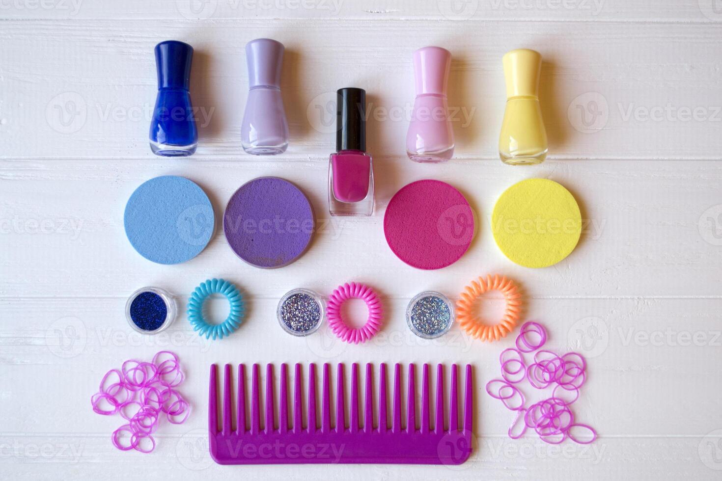 Colorful and bright cosmetics. Beauty care tools. Beauty salon. Girl's paradise. Nail polishes, sequins, pink hair bands and comb on the white wooden desk. Bright still life of beauty instruments. photo