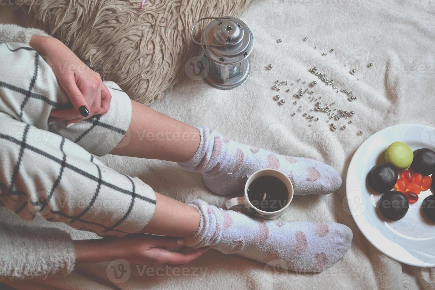 Woman relaxing in cozy place with sweets and a cup of tea. photo