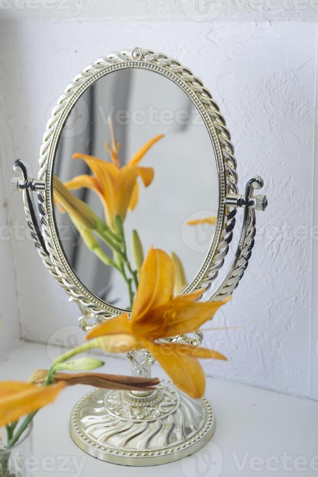 The orange lily near mirror. Flowers and mirror reflection. photo