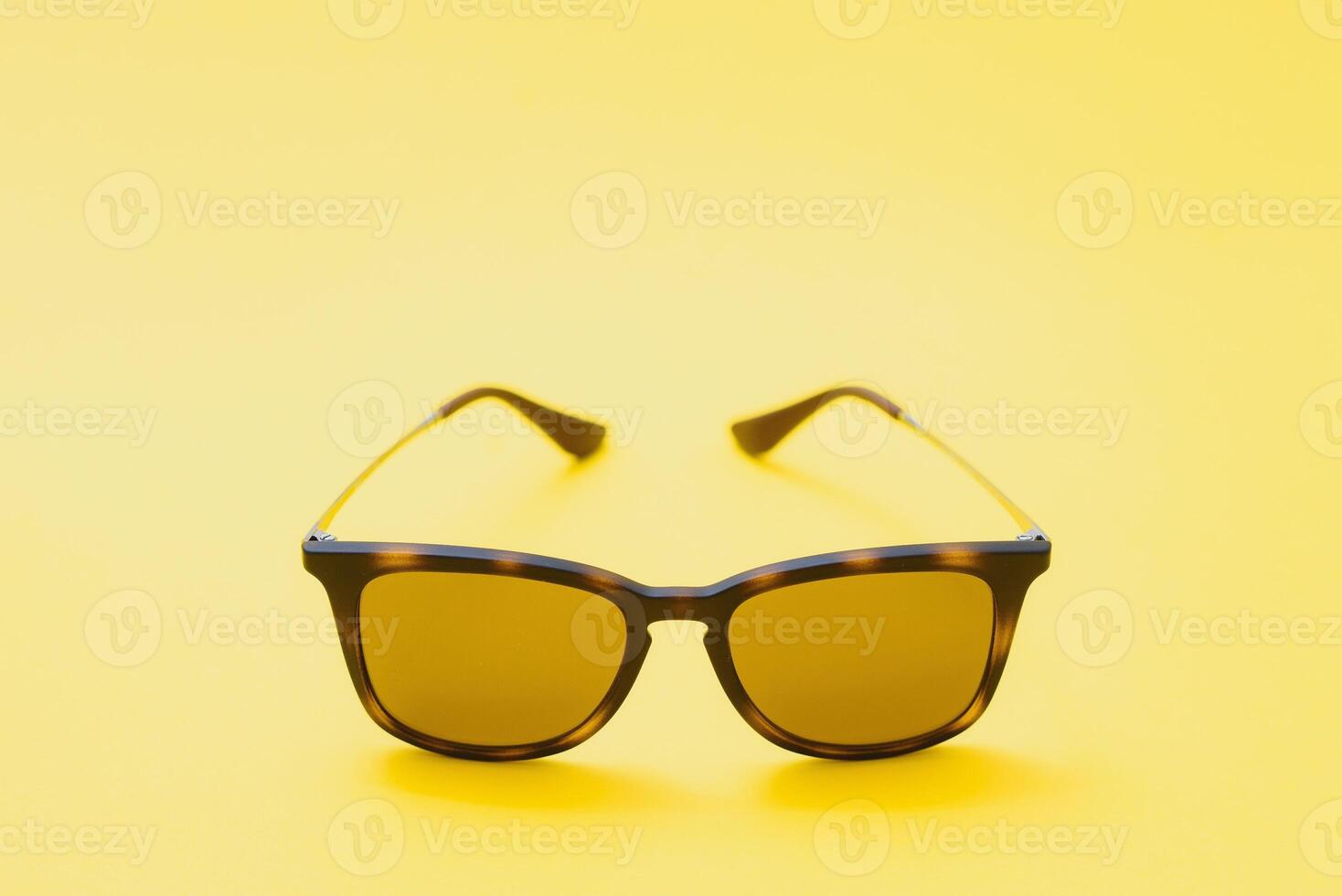 Brown glasses on yellow background photo