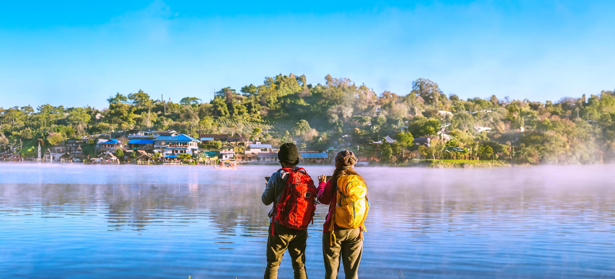 mujer asiática y hombre asiático que mochilero de pie cerca del lago, ella estaba sonriendo, feliz y disfrutando de la belleza natural de la niebla. foto