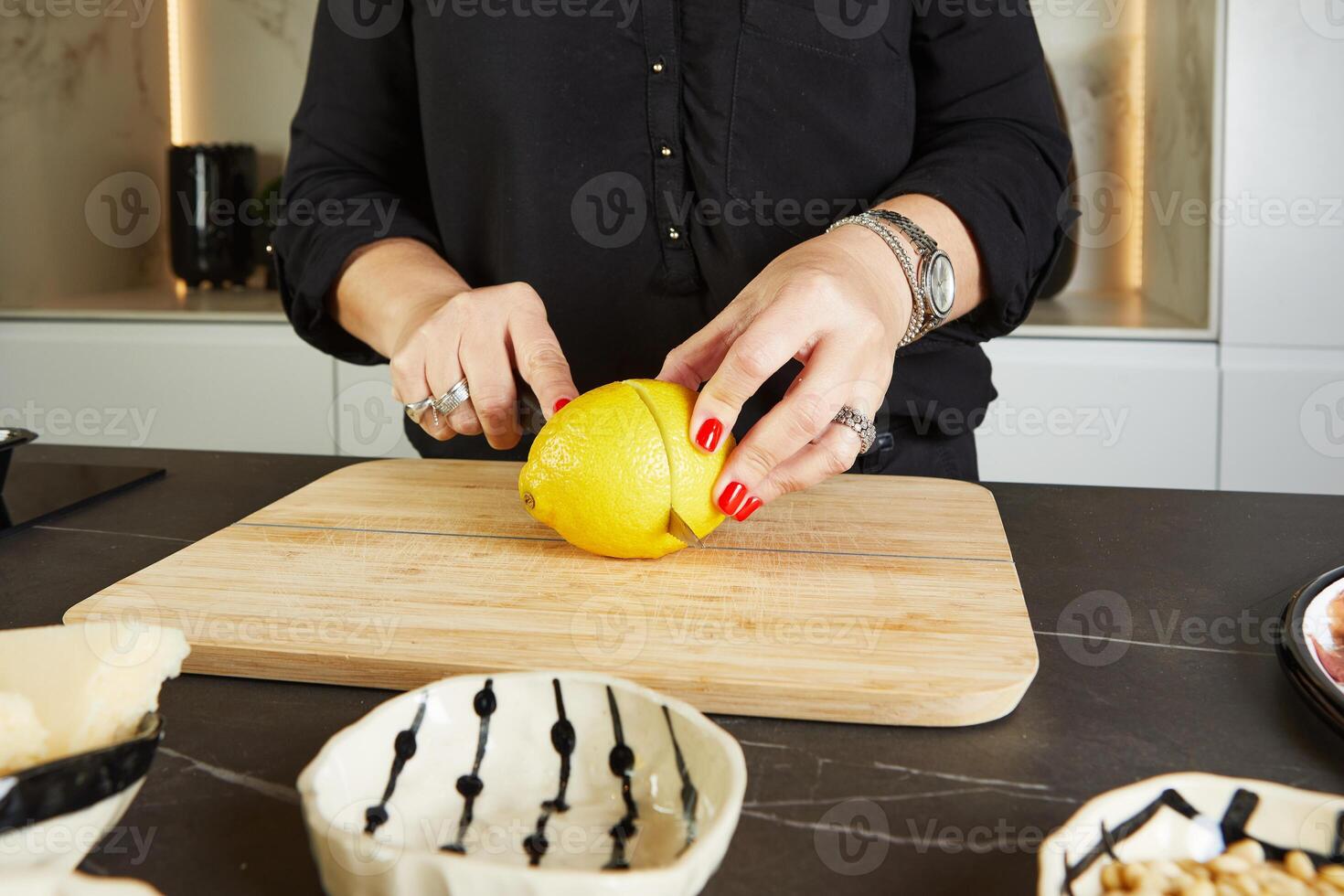 Hostess cutting lemon in kitchen for carpaccio making with marble background photo
