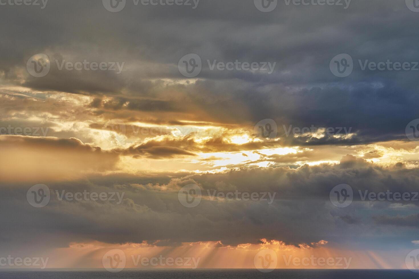 Dramatic thunderclouds over mediterranean sea with sun rays breaking through photo