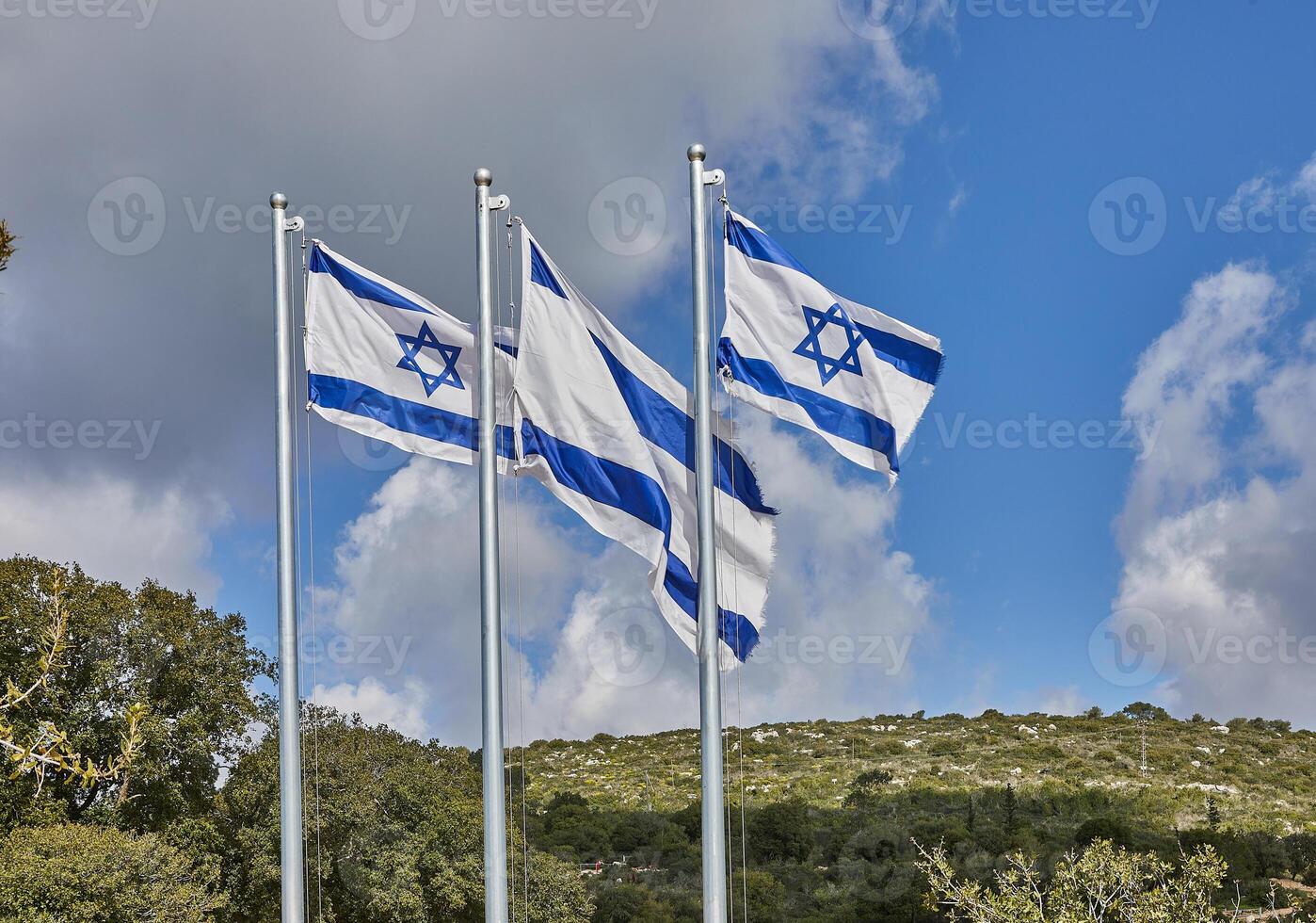 Four Israeli flags proudly waving under the blue sky with hills in the background photo