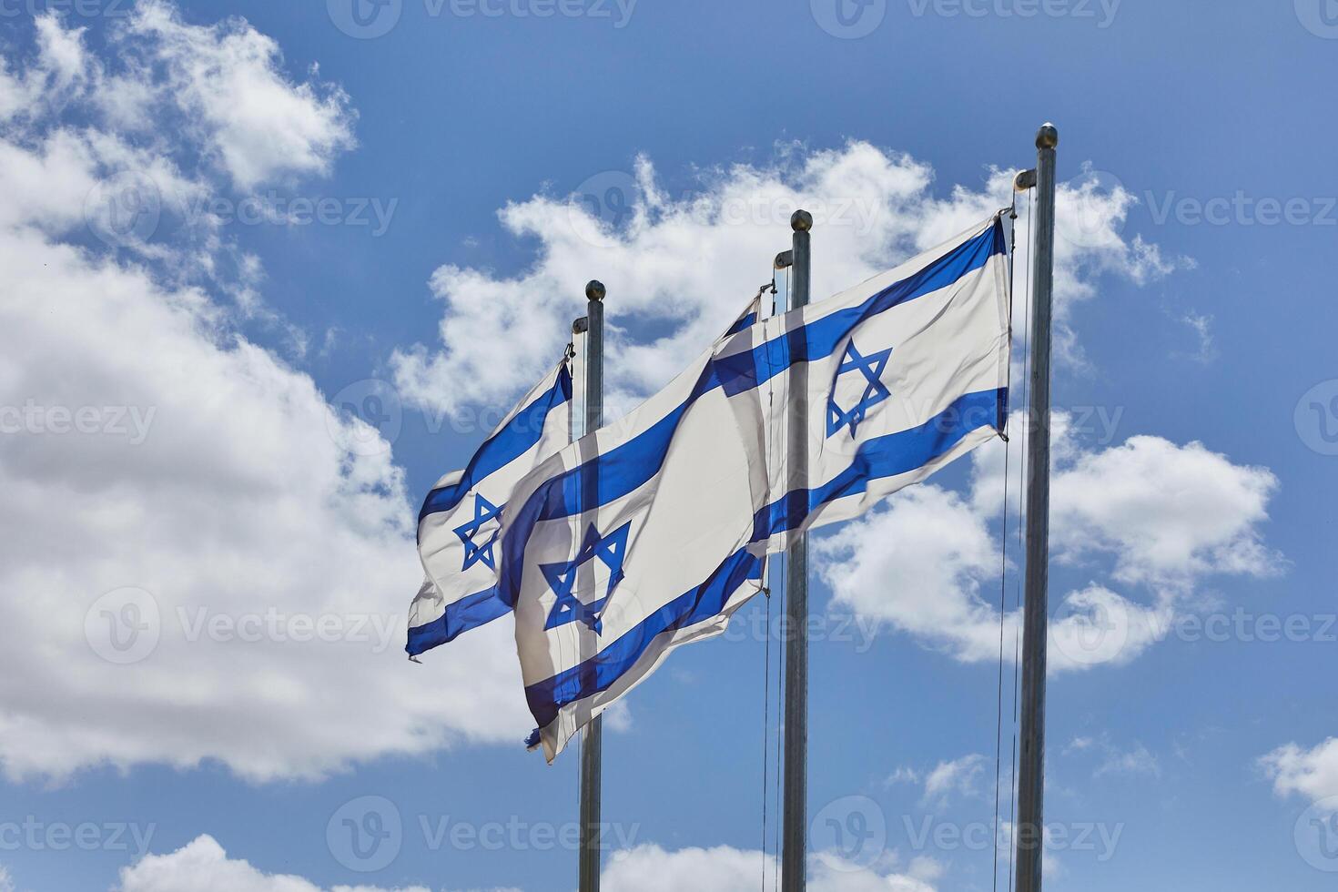 Four Israeli flags proudly waving under the blue sky with hills in the background photo