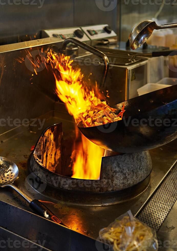 a wok is cooking food on a stove with flames coming out of it photo