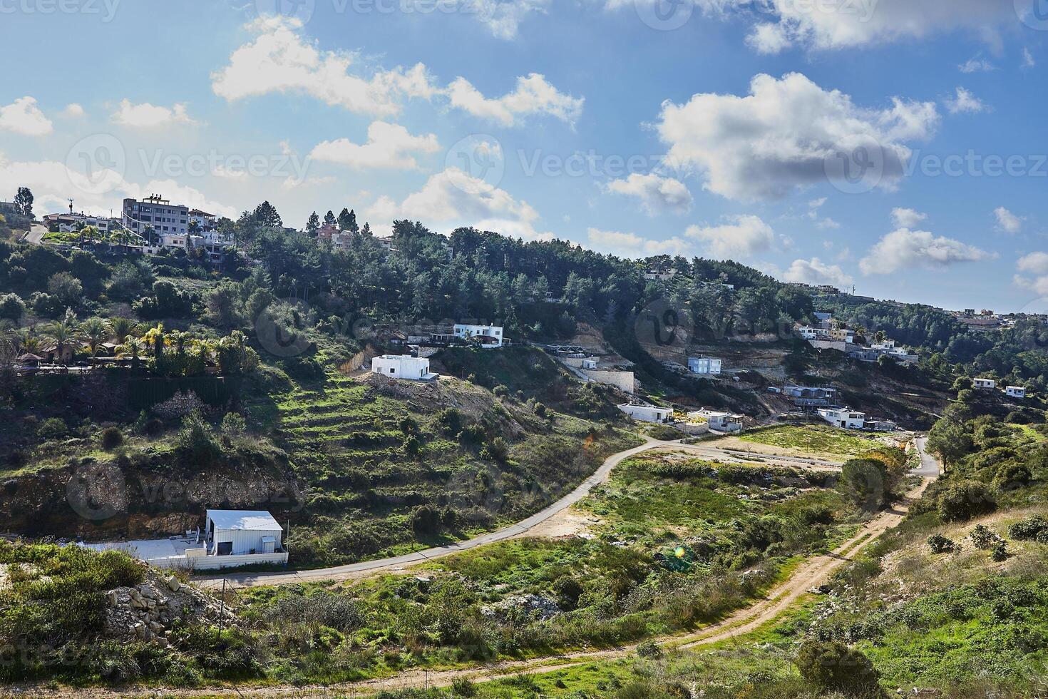 A scenic view of a town in the countryside with a blue sky and white clouds in the background photo