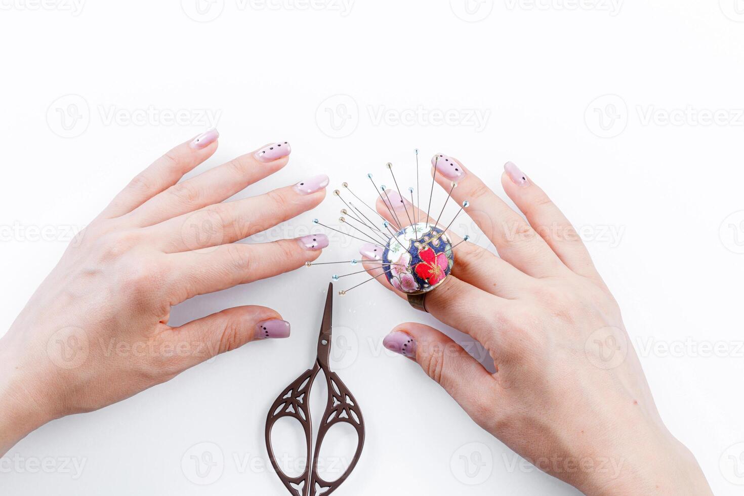 a ring with a small pillow for needles on a hand and scissors on a white background photo