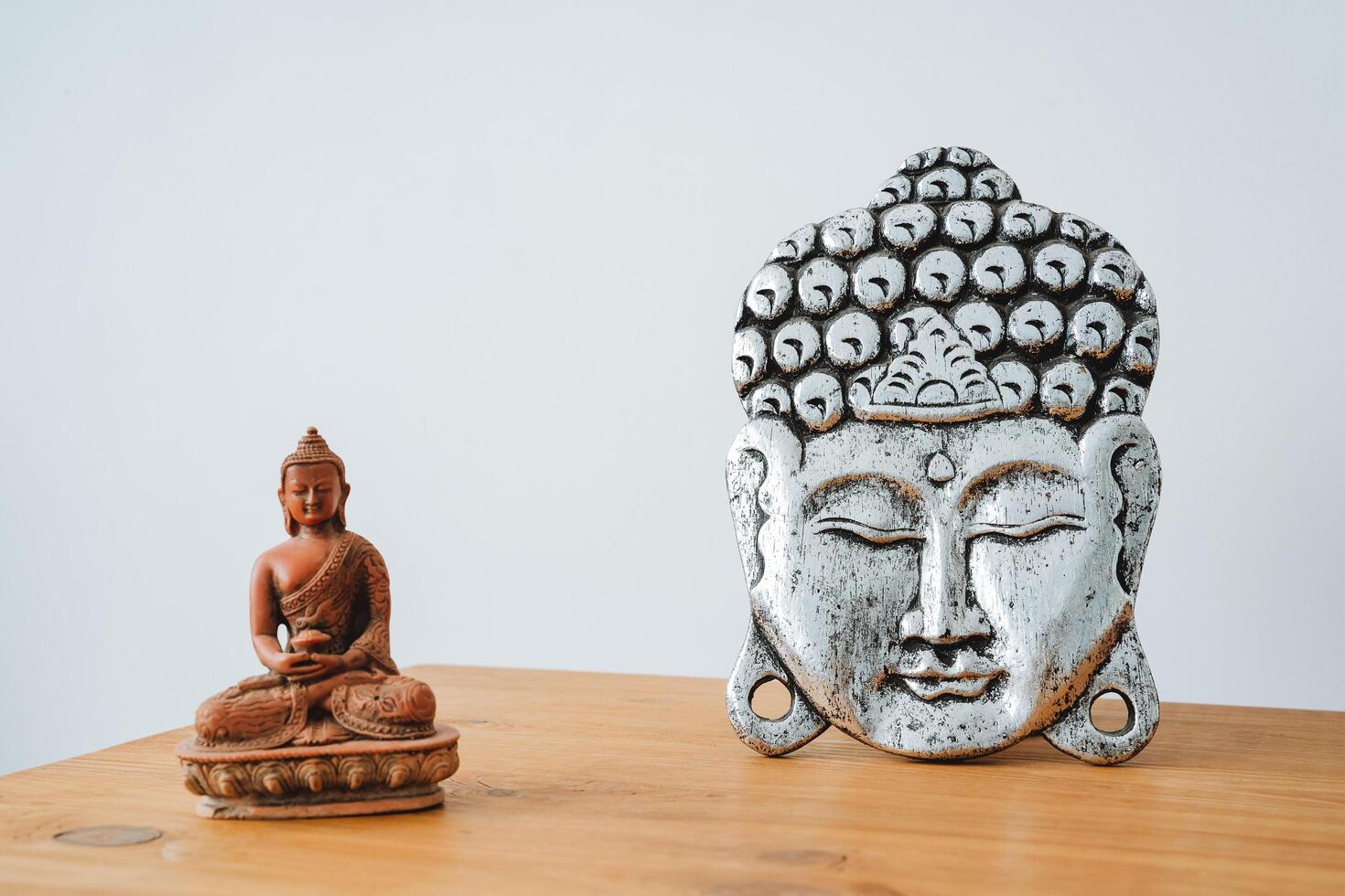 The image of the Buddha is on the table. The buddha's head is silver in color. The statuette is small in Buddhism. photo