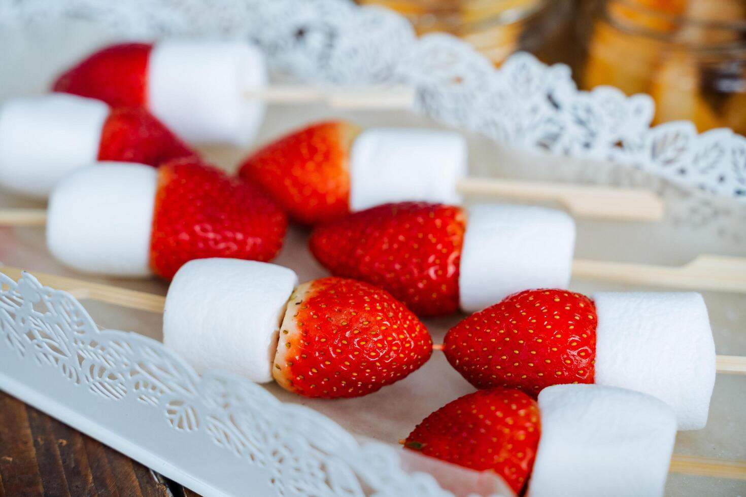 Bright red strawberries and marshmallows on a skewer. Ingredients for fondue and canapes. Sweet and healthy desserts with berries. photo