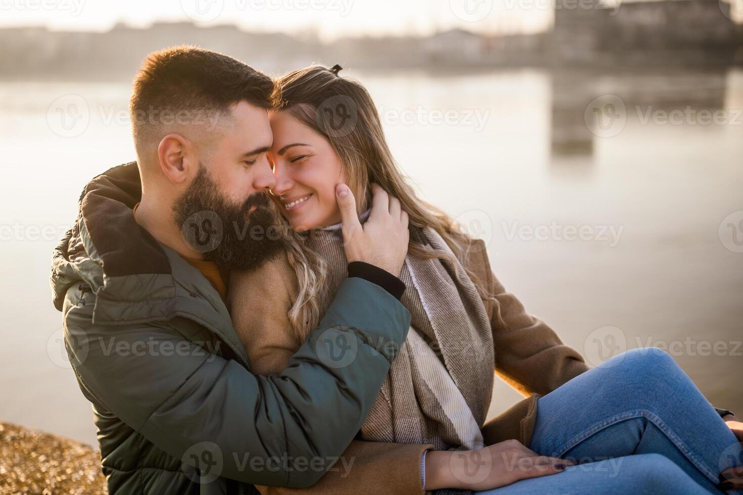 Happy couple embracing while  enjoy sitting by the river. photo