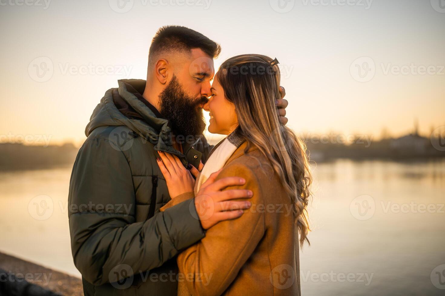 Happy couple enjoy spending time together outdoor on a sunset. Man is kissing his woman in nose. photo