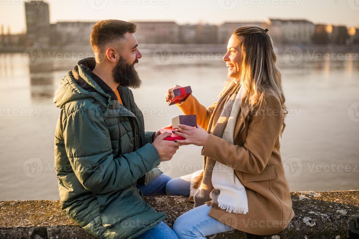 Man giving presents to his woman while they enjoy spending time together outdoor. photo