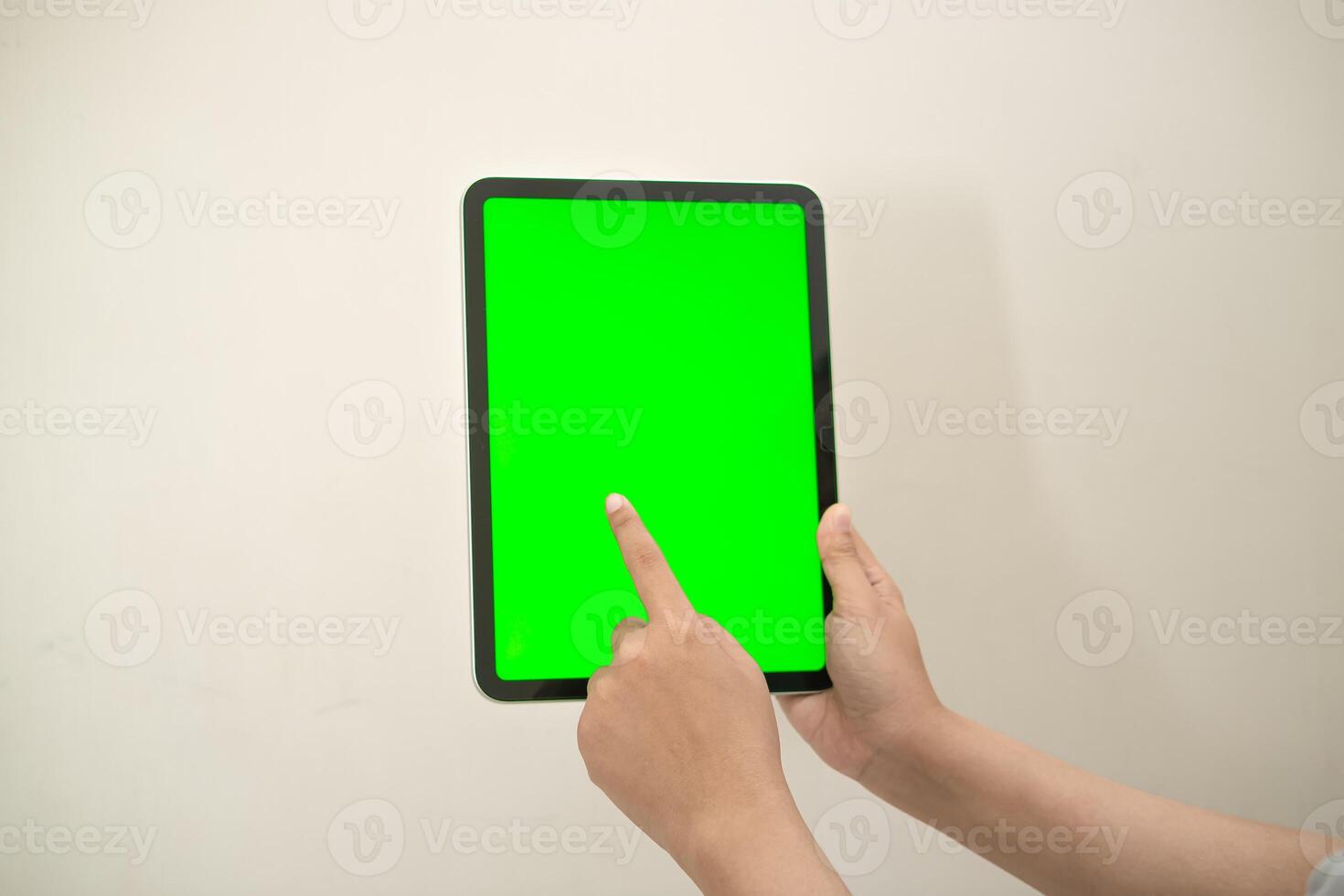 hand is holding a tab with green screen on a white isolated background photo