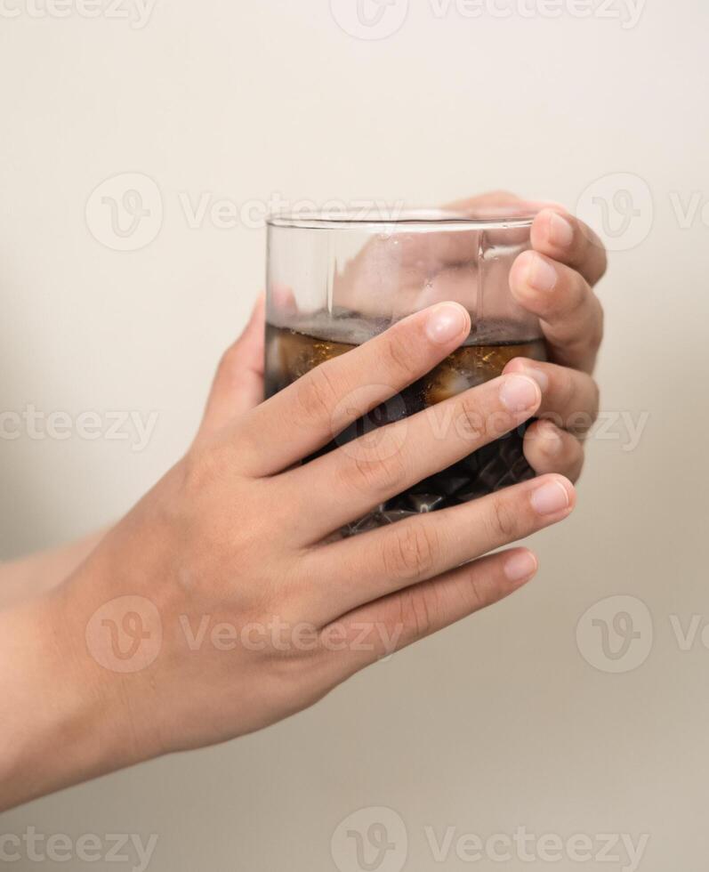 hand is holding a glass of coffee with ices on a white isolated background photo