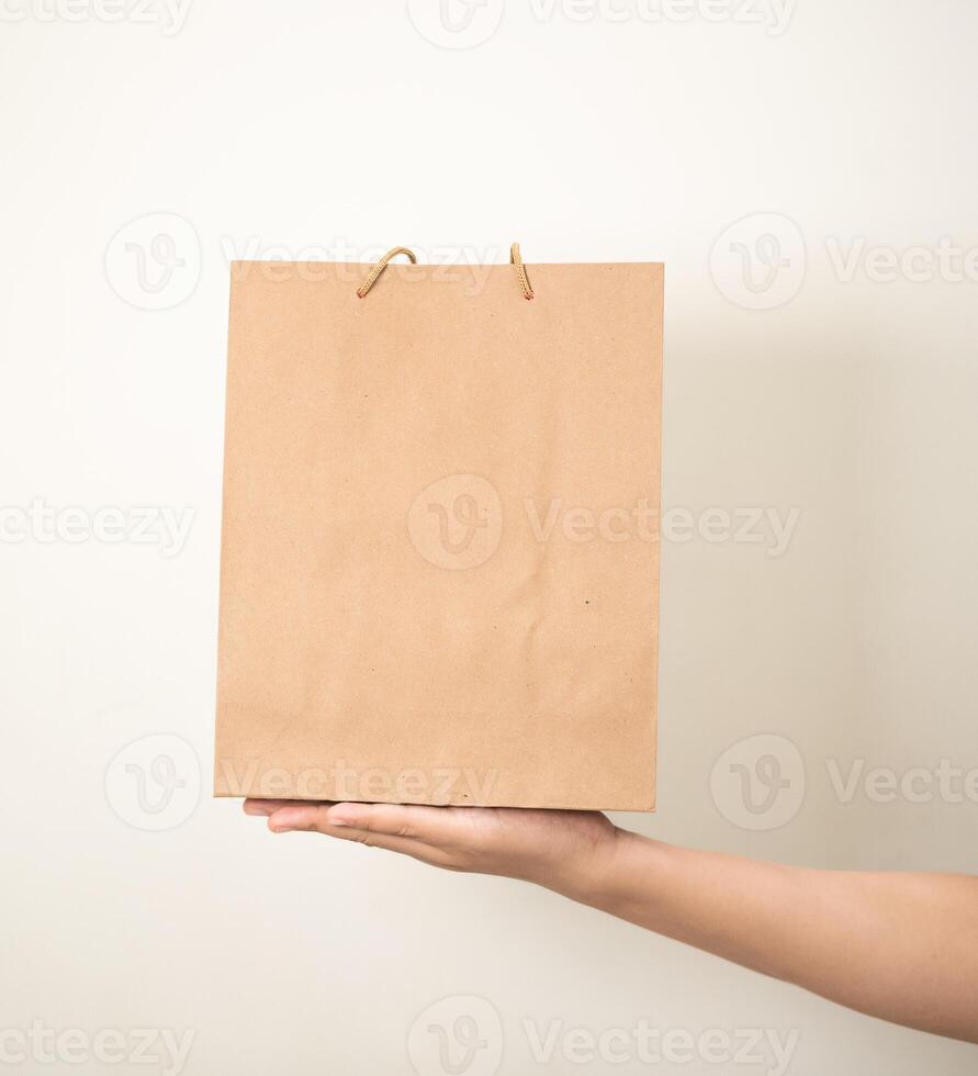 hand holding a shopping paper bag against a white isolated background photo