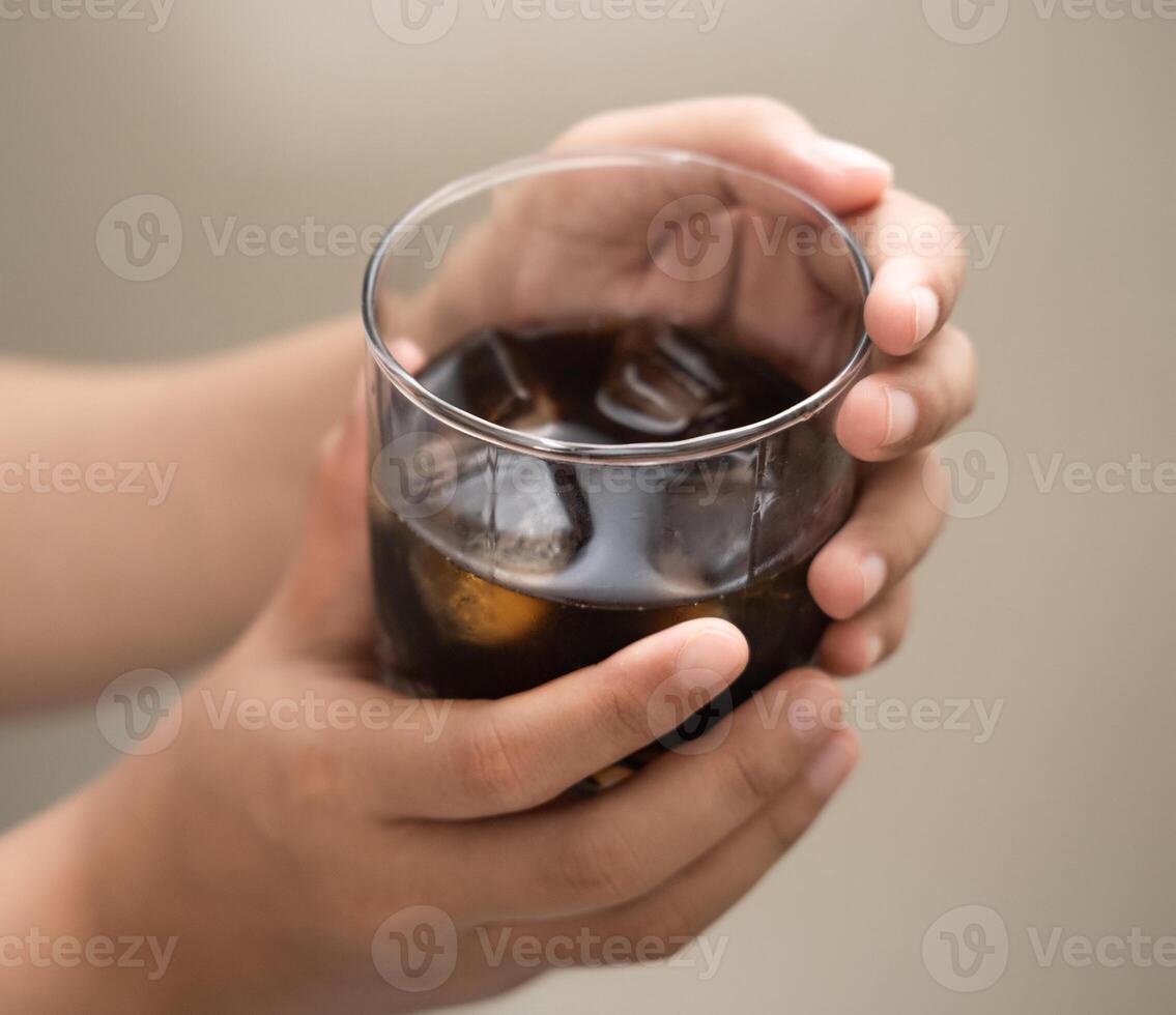 hand is holding a glass of coffee with ices on a white isolated background photo