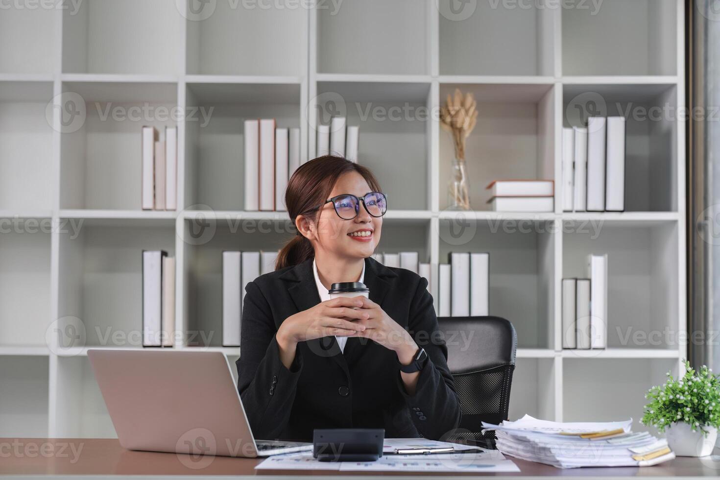 Portrait smiling Asian business woman uses laptop to work on financial transactions. Planning work on the desk in the office photo