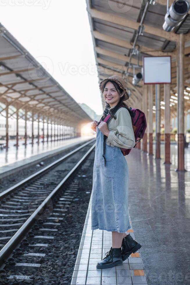Young Asian woman in modern train station Female backpacker passenger waiting for train at train station to go on holiday. photo