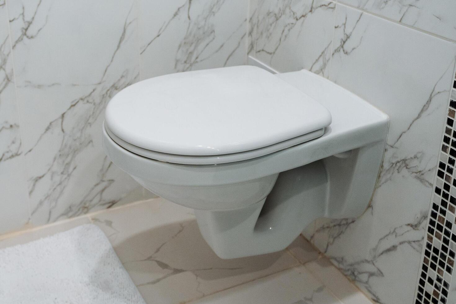 White ceramic toilet hanging on the wall, toilet room, closed toilet cover, plumbing fixed to the wall, restroom. photo