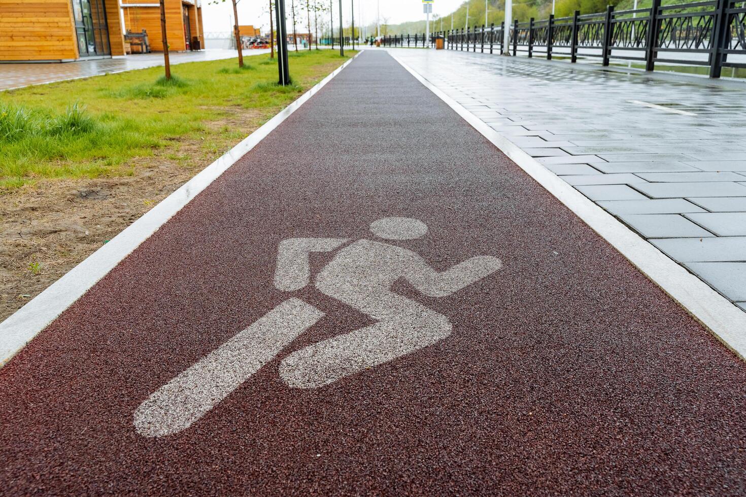 Red treadmill, silhouette of a person sign on the sidewalk, rubber road surface for athletes runners, city park active recreation place for sports photo