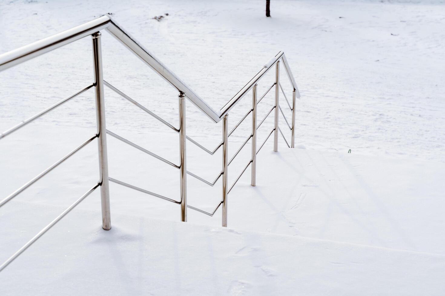 metal escalera con barandillas en el calle. el pasos y barandillas de el escalera son cubierto con nieve. suavemente descender y ascender foto