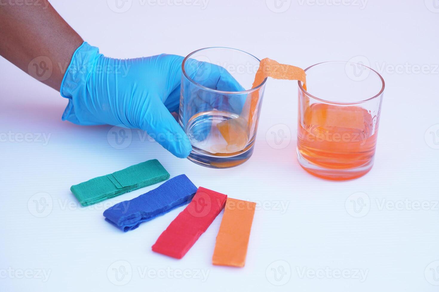 Hand wear blue glove, hold glass of color paper strip to absorb water to another glass. Concept, science lesson activity. Easy experiment for learning. Teaching education materials. Learning design photo