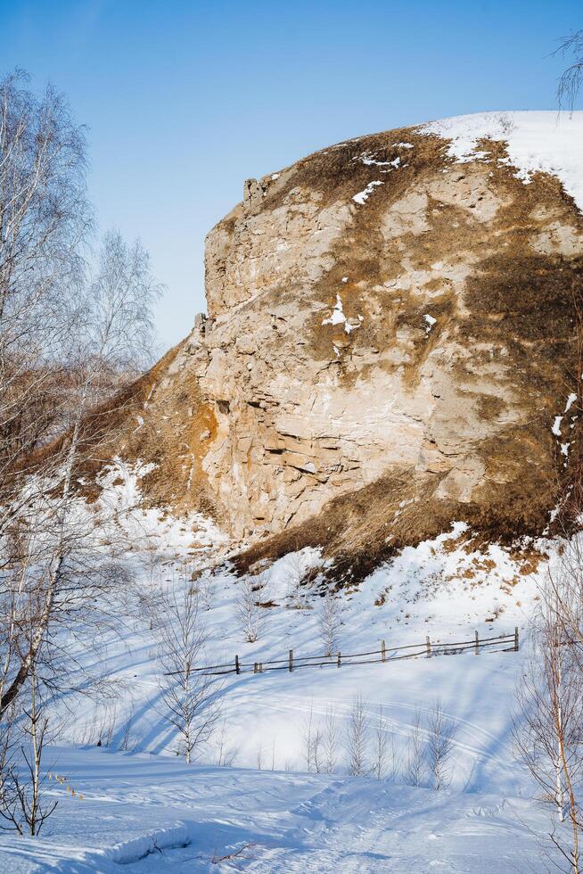 A rock against the sky in clear weather, snow lies in the mountains, spring weather early in the morning, steep rock, a journey through the mountains photo