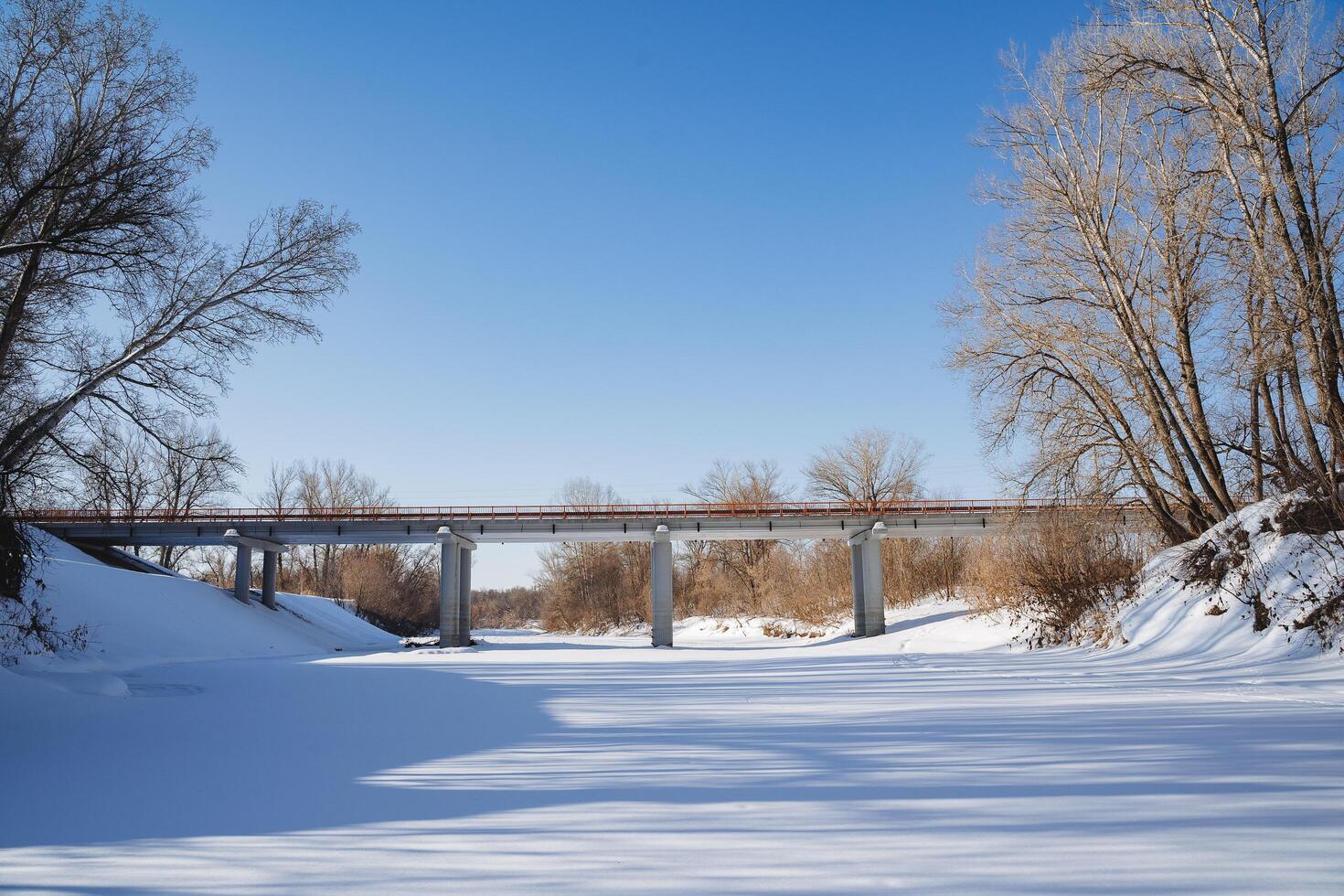un la carretera puente cruces un congelado río. paso superior para transporte mediante agua cubierto con hielo y nieve. invierno en el norte de Rusia. foto