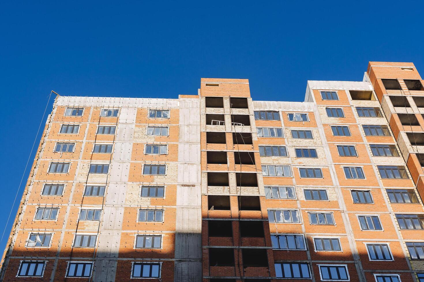 The house is made of red brick against the blue sky. Construction of the building from concrete view from the outside. Facade of the house. photo