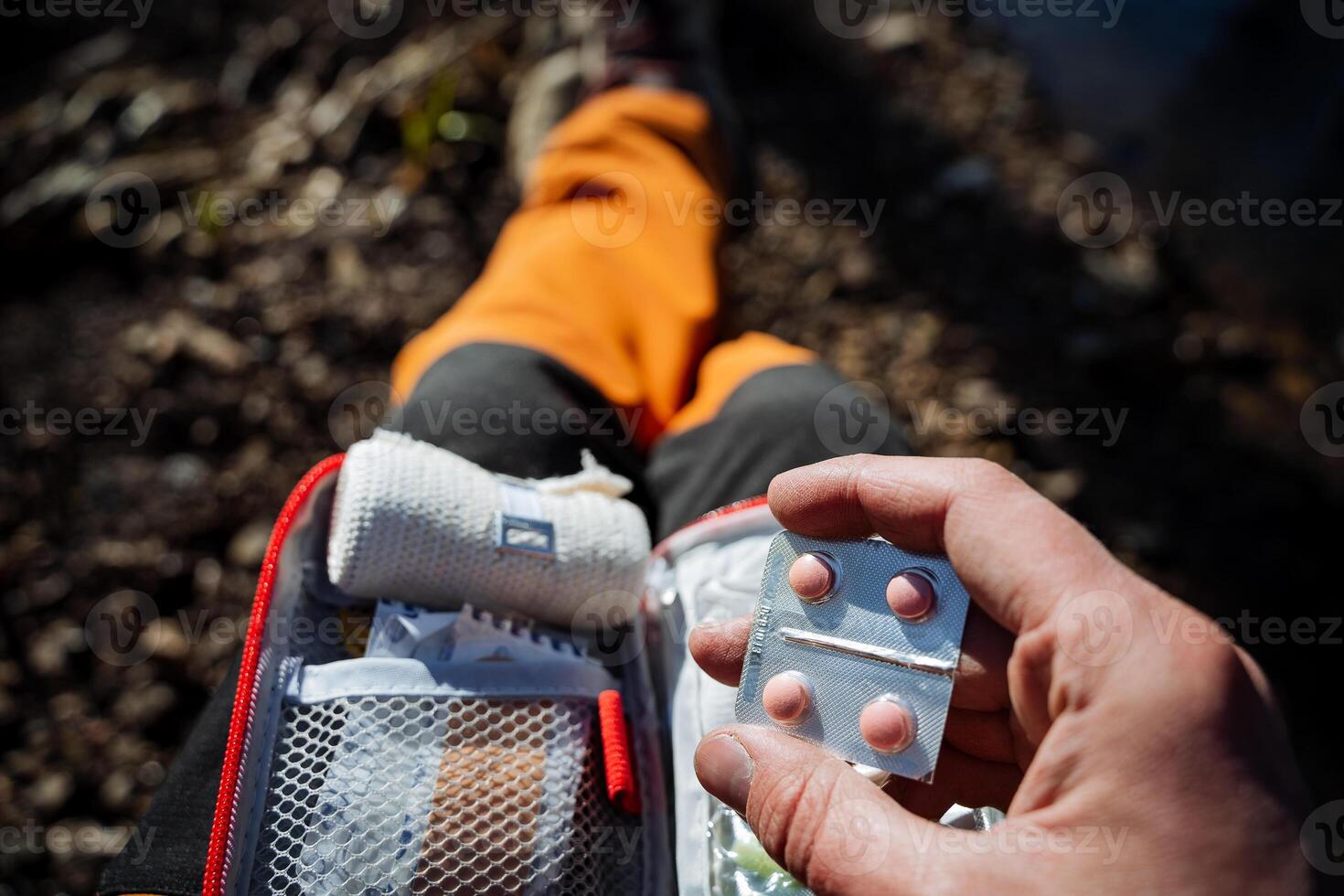 Pink pills, first aid kit, elastic bandage, the tourist takes a pill for nausea. the hand holds the medicine. photo