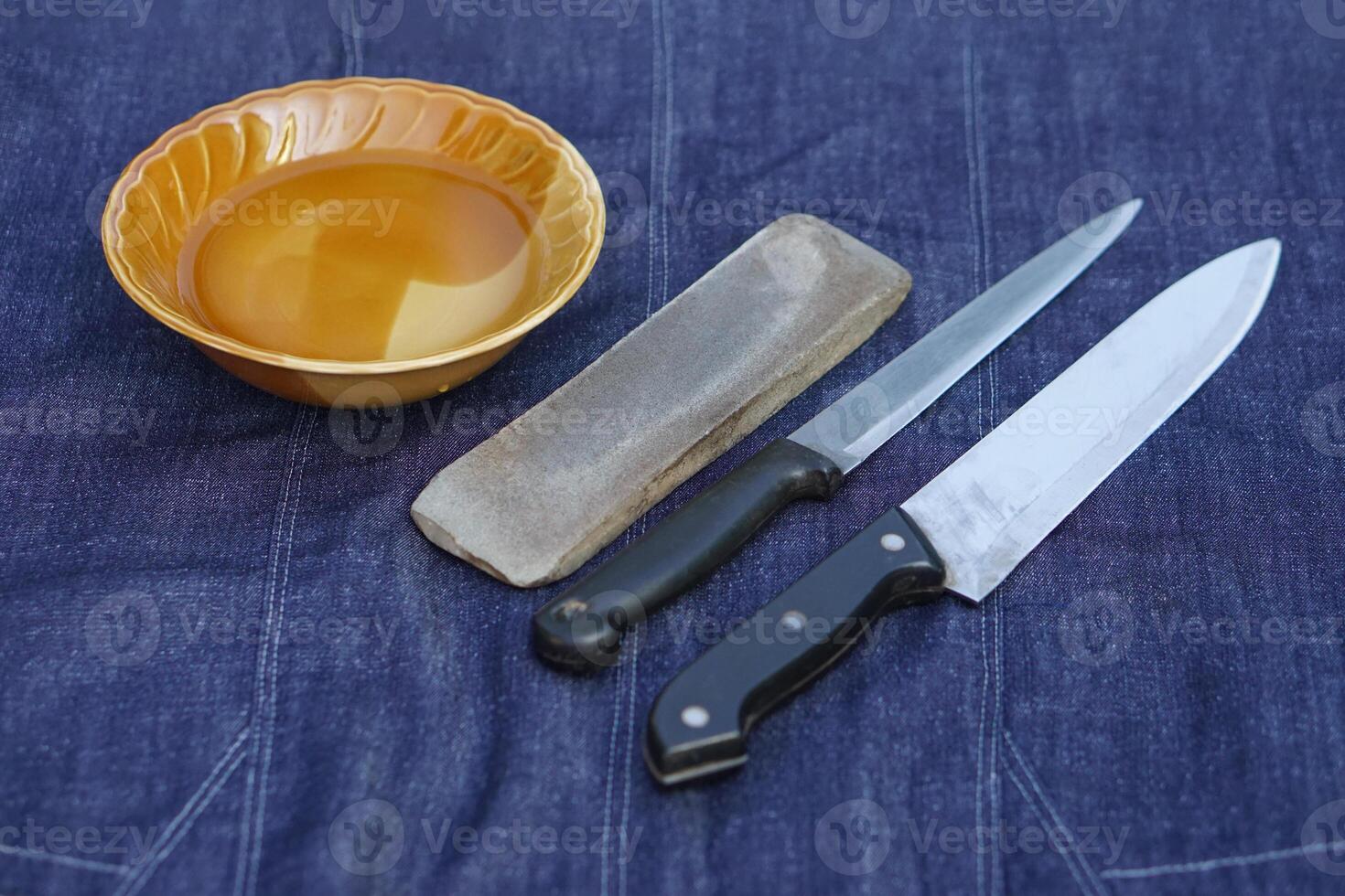 Bowl of water, grinder stone and knives, prepare for sharpening. Concept, maintenance tools for cooking, make knife sharp ,not dull for long live using. Original style for sharpen knife. photo