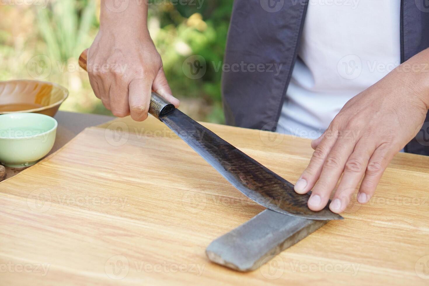 Closeup man hands sharpen knife on whetstone sharpener or grindstone. Concept, maintenance tools for cooking, make knife sharp ,not dull for long live using. Original style. photo