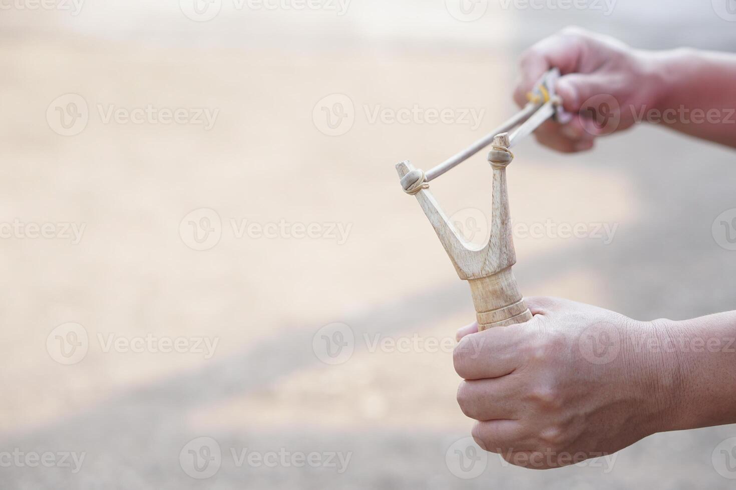 Close up hands hold wooden slingshot for playing shooting game. Concept , Thai traditional weapon that use to shoot birds, fish , for fight game or other purposes. photo
