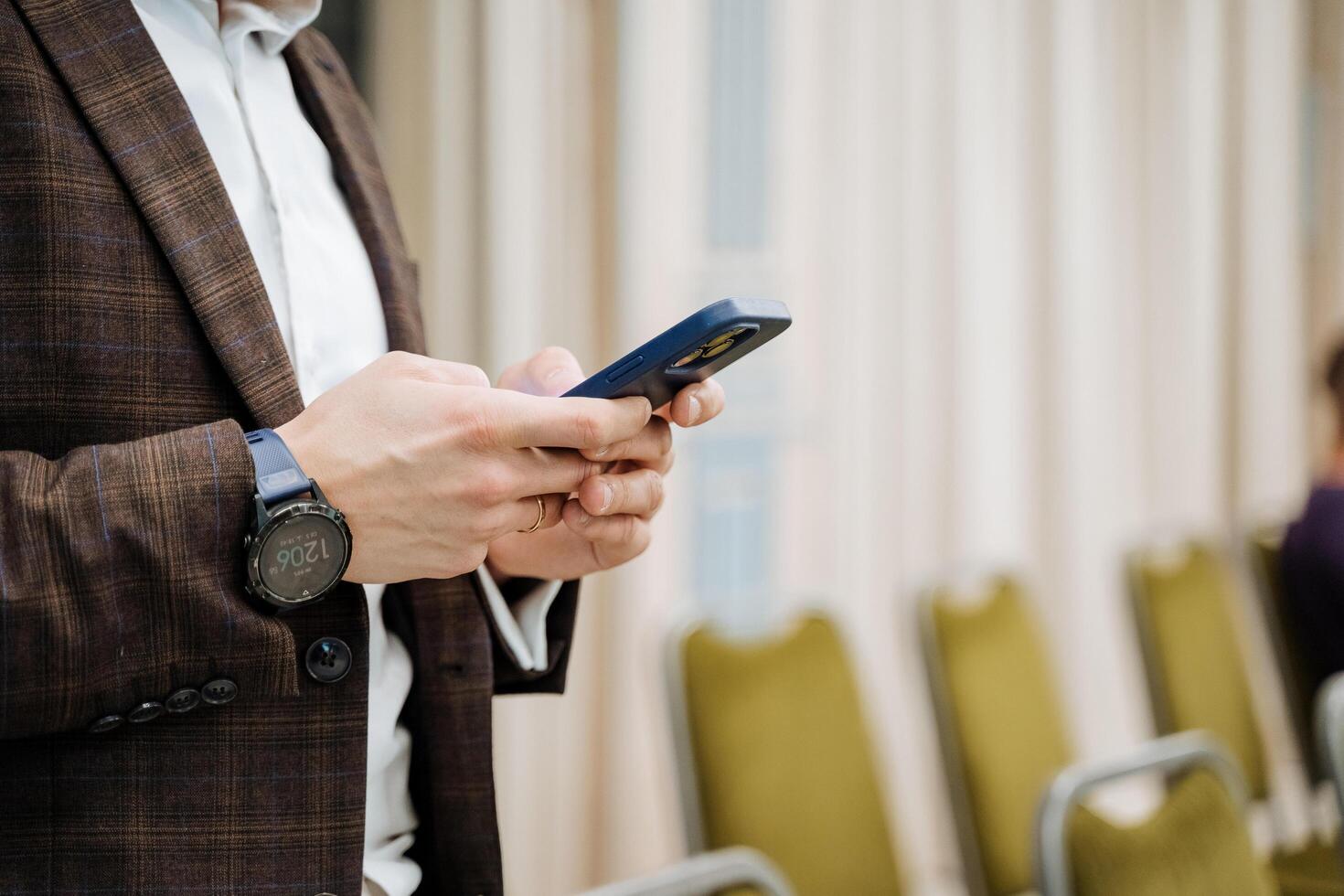 The guy writes a message on his phone. Smartphone in the hands of a man. Type sms with your fingers in the mobile phone application. Watch on hand. A businessman at work. photo