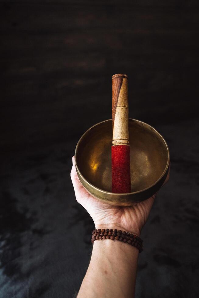 A Tibetan singing bowl is in the hand. A subject for meditation and healing sounds. Zen practice. Rudraksha bracelet on the arm. photo