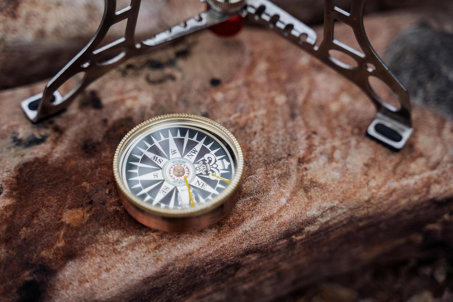 A brass compass lies on a rock in nature, orientation in the forest, the direction of the north is shot close-up. photo