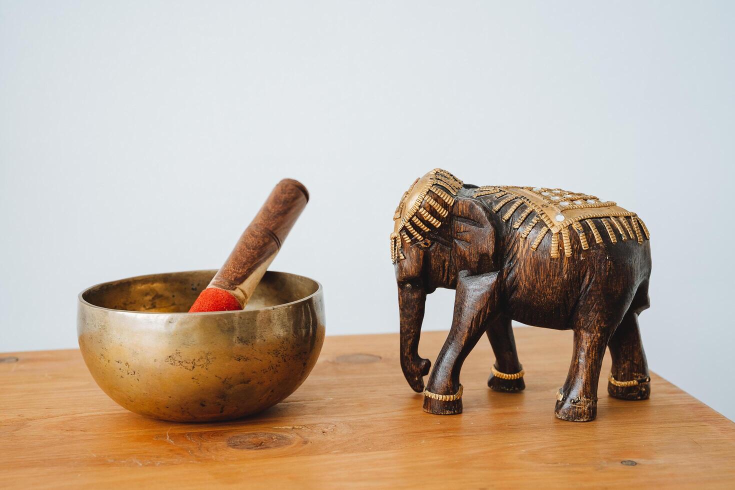 tibetano cuenco soportes en un mesa un de madera figurilla de un elefante caminando adelante maletero bajado abajo objetos para yoga. foto