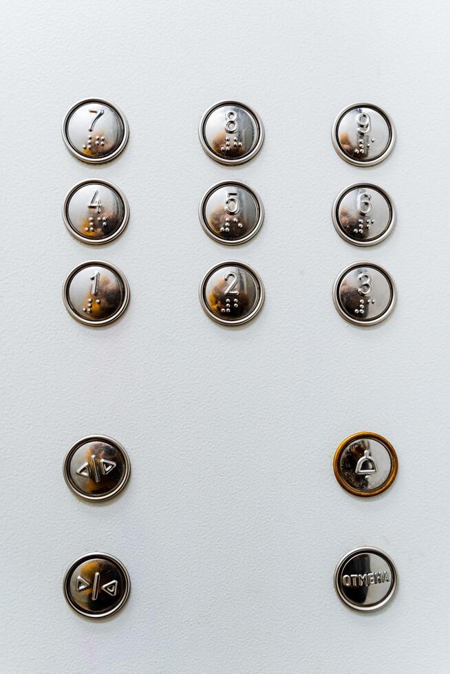 un cerca Disparo de el multifunción ascensor botón panel. en el botón de el inscripción para el ciego. Vamos a el deseado piso por ascensor foto