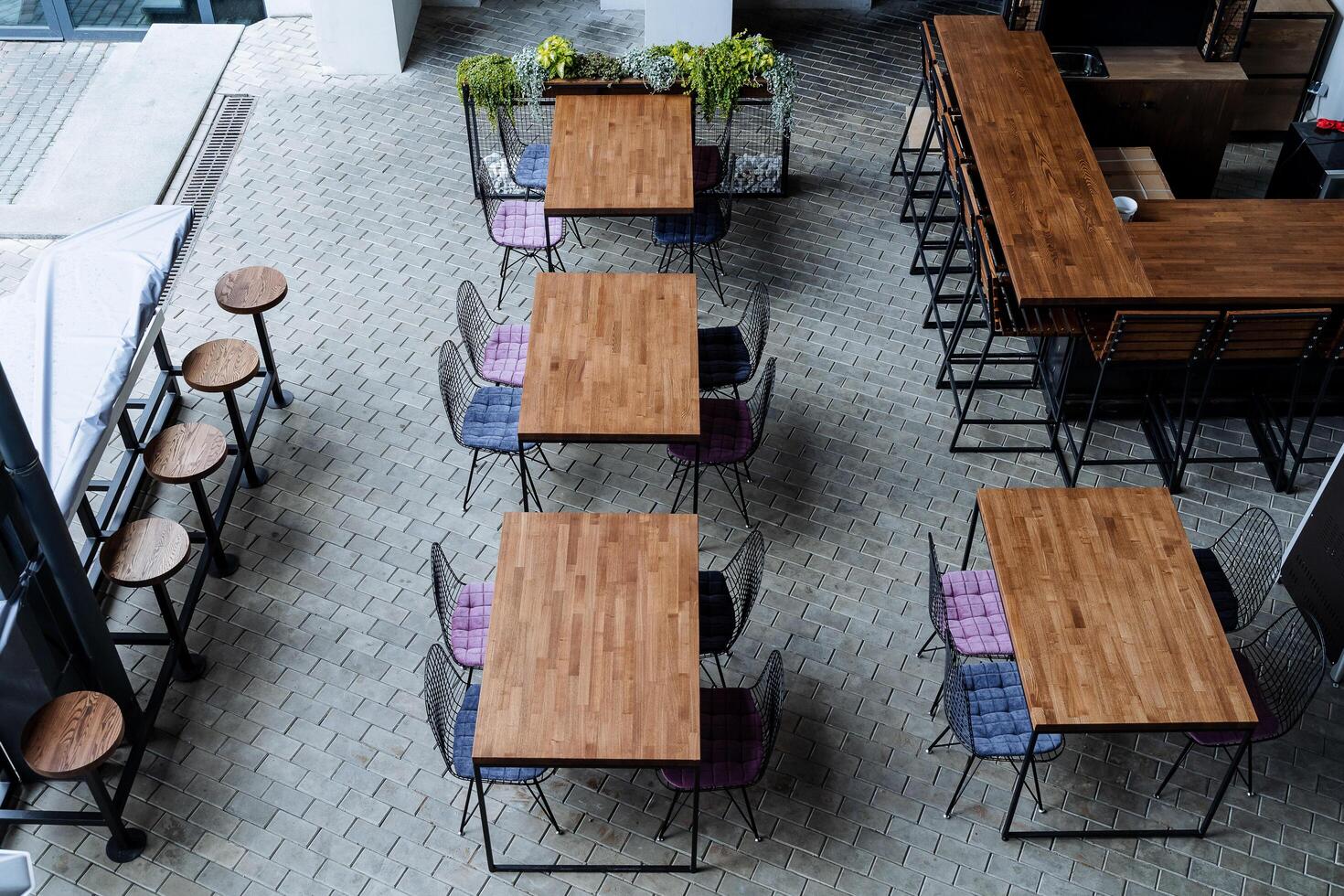 un ciudad calle cafetería, un rápido comida establecimiento, un recreación zona para los ciudadanos, vacío mesas estar en el calle, un bar encimera, diseñador muebles, un restaurante debajo el cielo. foto