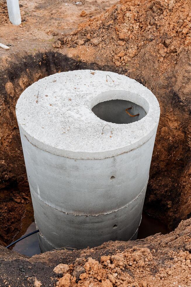 Suburban construction installation of concrete sewer rings, a treatment facility for the house, a round septic tank buried in a pit. photo