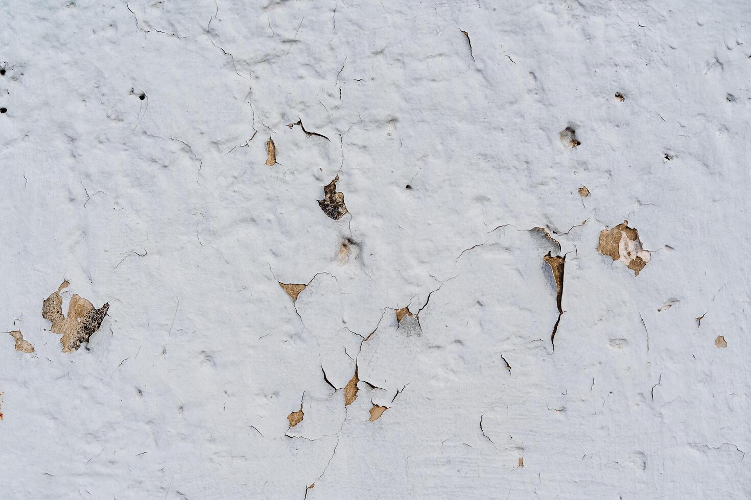 An old white wall with tearing plaster. The cracked surface of the wall. Textured surface. Renovation required photo