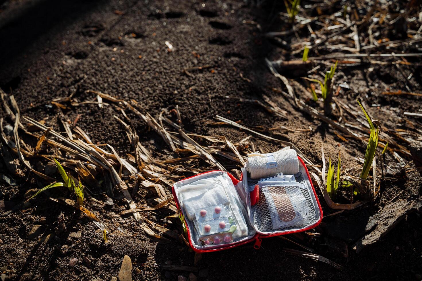 First aid kit in difficult hiking situations. Medicines for a tourist, a bag with pills lies on the ground, an open first-aid kit helps a person lost in the forest. photo