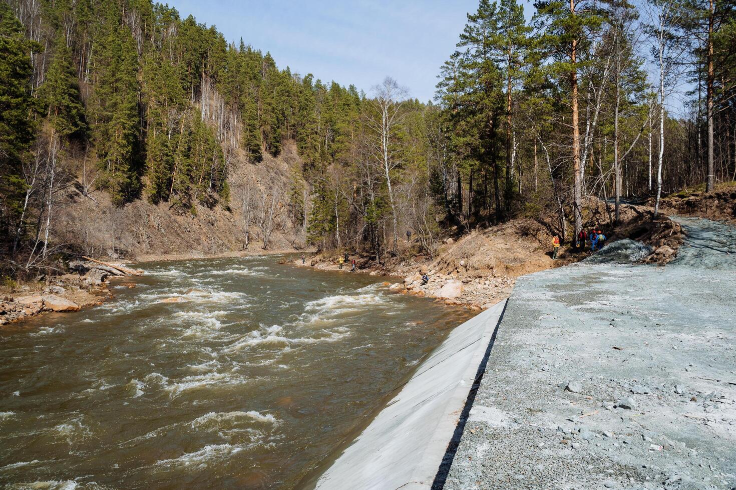 A concrete structure on the bank of a mountain river, a fence to protect the shore from destruction, a mountain river turbulent stream. photo