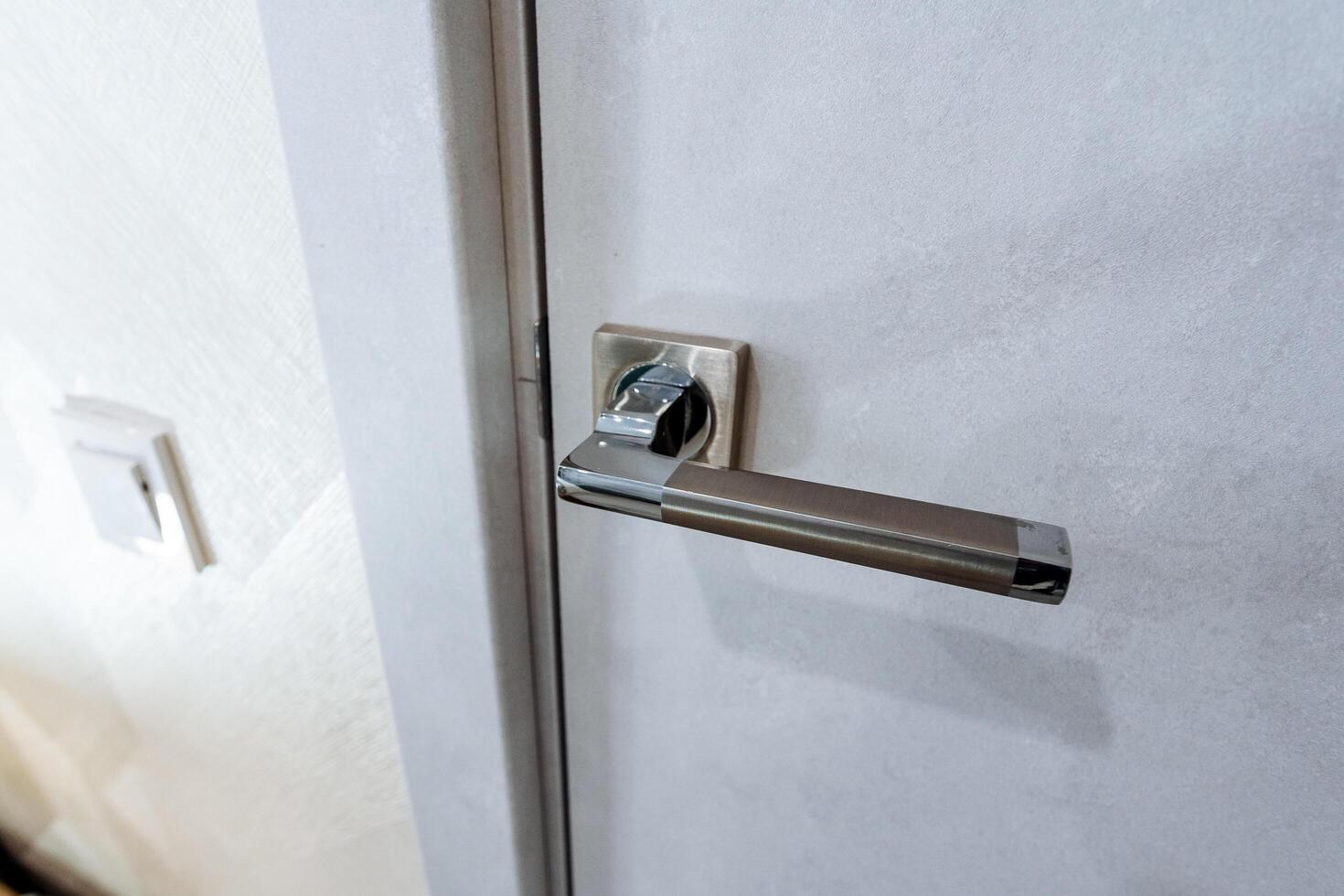 Door handle chrome plated, door to the room locked, door handle shot close-up, grey door, interior of the room photo